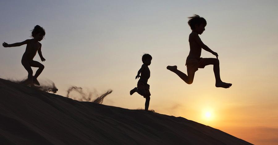 Children running down a sand dune